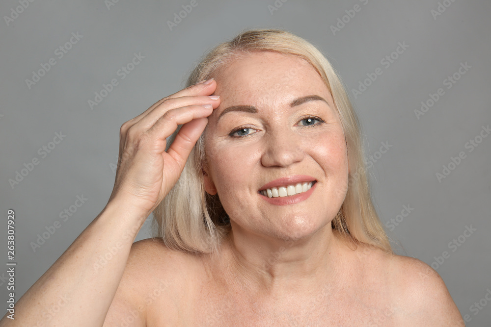 Mature woman with healthy skin on grey background