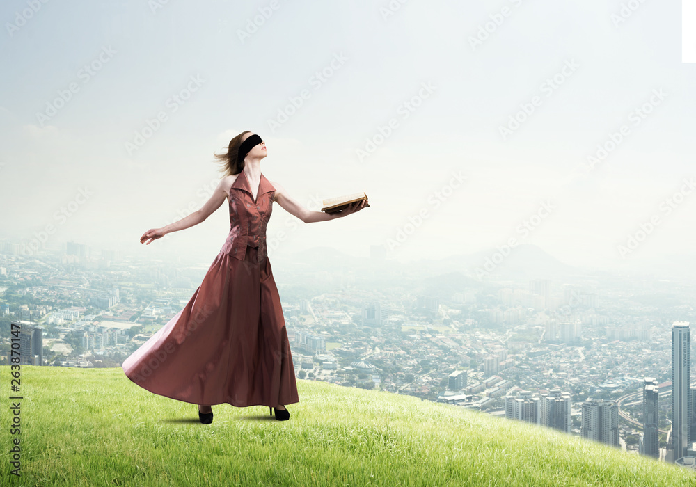 Girl against cloudy sky with opened book in palm as idea for knowledge