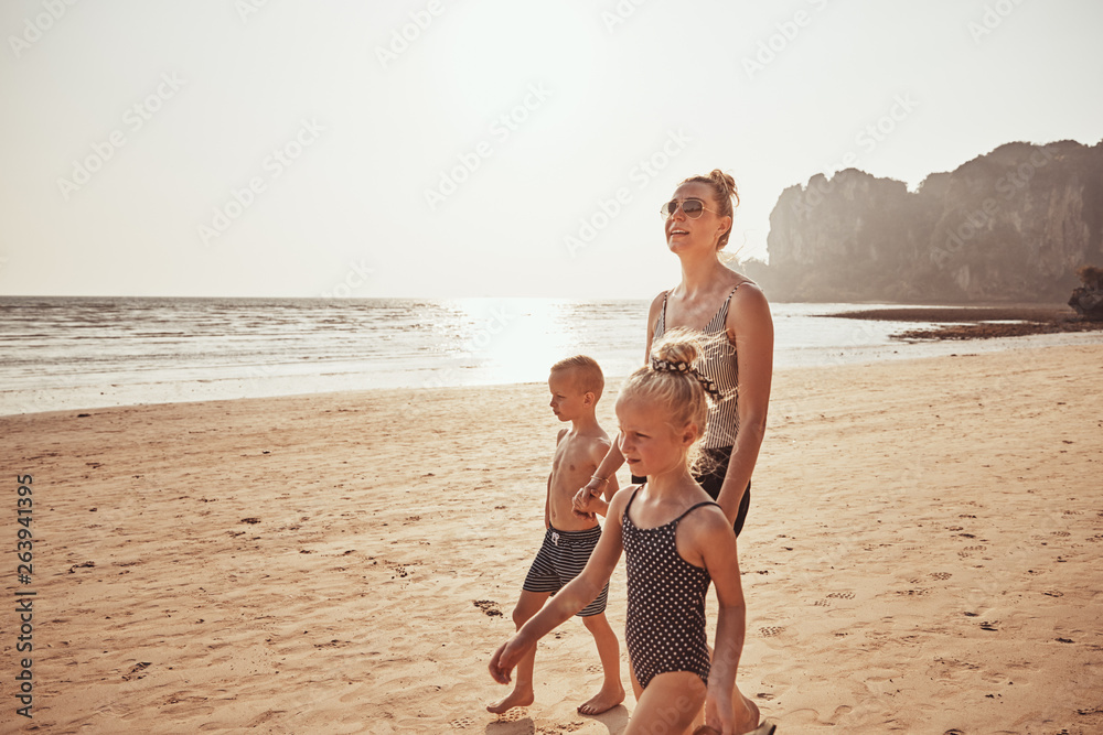 Smiling Mom and two children walking along a sandy beach