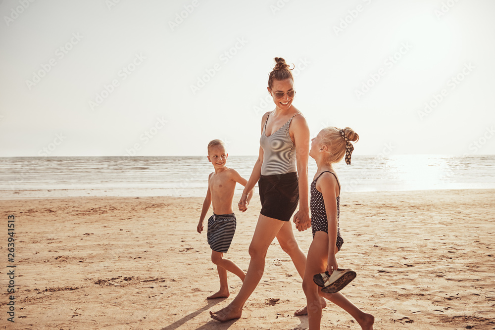 Smiling Mom and her kids walking along a sandy beach