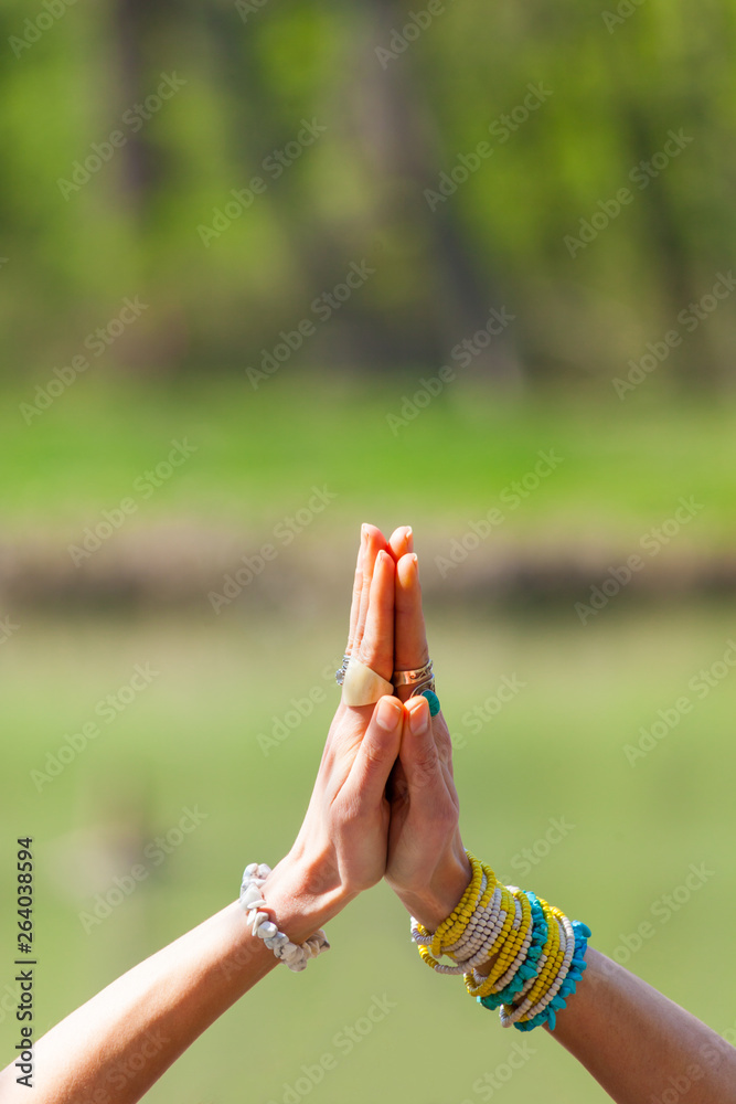 woman hands with lot of rings and bracelets in yoga mudra gesture namaste greeting outdoor shot sunn