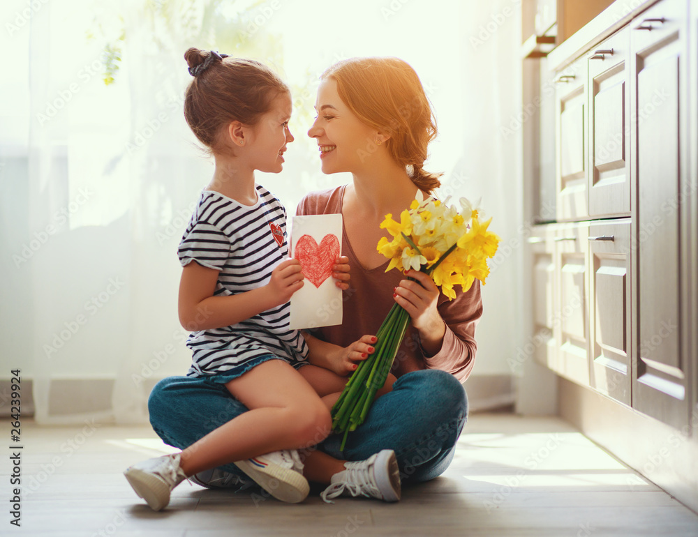 happy mothers day! child daughter   gives mother a bouquet of flowers to narcissus and gift.