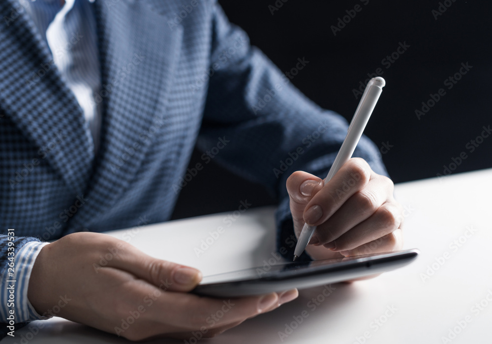 Man in business suit sitting at desk with tablet