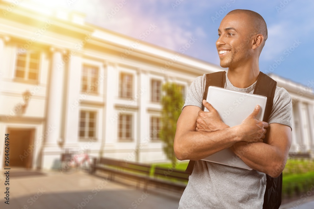 Young man student in grey shirt holding notebook and smile