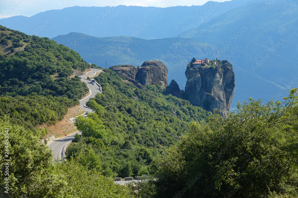 AERIAL: Flying towards a scenic country road leading towards a town on a cliff.