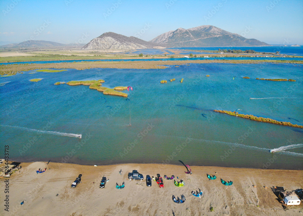 空中娱乐：体育游客在希腊海边多风的海湾周围风筝冲浪。