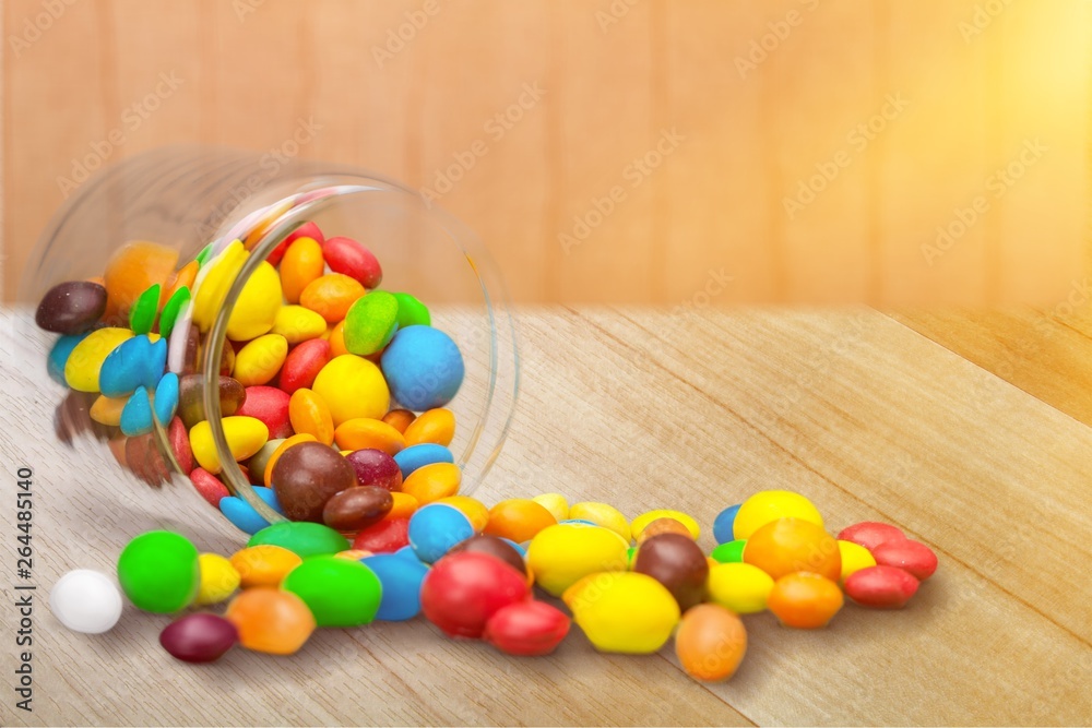 Colorful candies sweets falling out of a glass jar, composition isolated over the white background