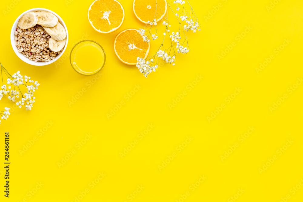 food for healthy breakfast with granola and fresh orange juice on bright yellow background top view 