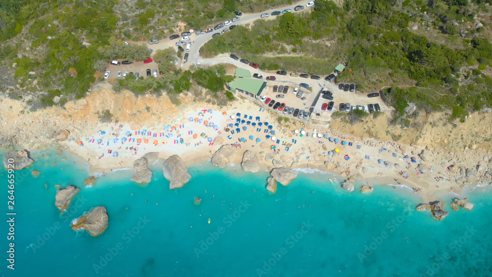 TOP DOWN: Flying above crowded white sand beach full of colorful umbrellas.