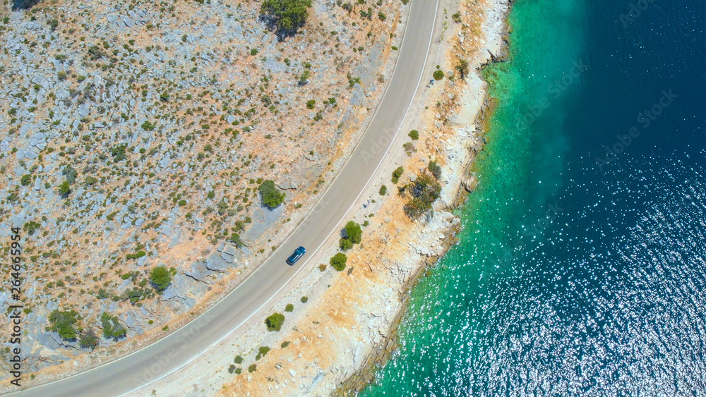 DRONE: Flying above tourist car driving along the beautiful glistening ocean.