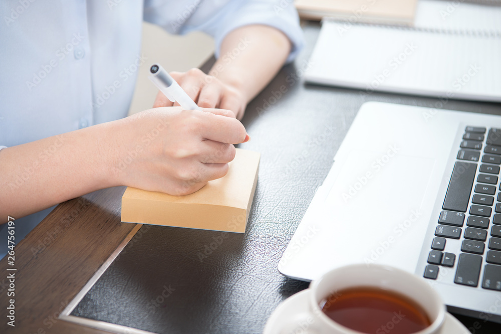 Business concept. Woman takes note for project with laptop and report in office desk. Backlighting, 