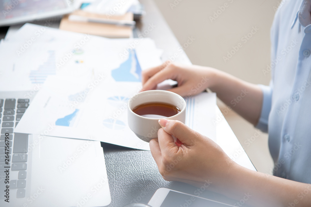 Business concept. Woman reading reports and drinking for rest in office table. Backlighting, sun gla