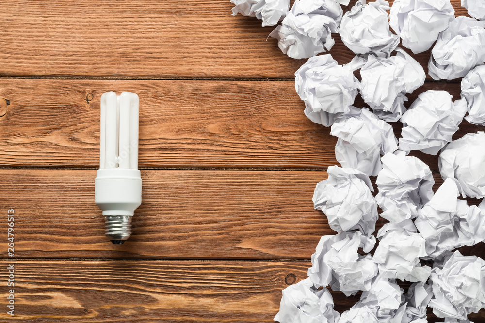 Ideological concept with wastepaper light bulb on wooden table