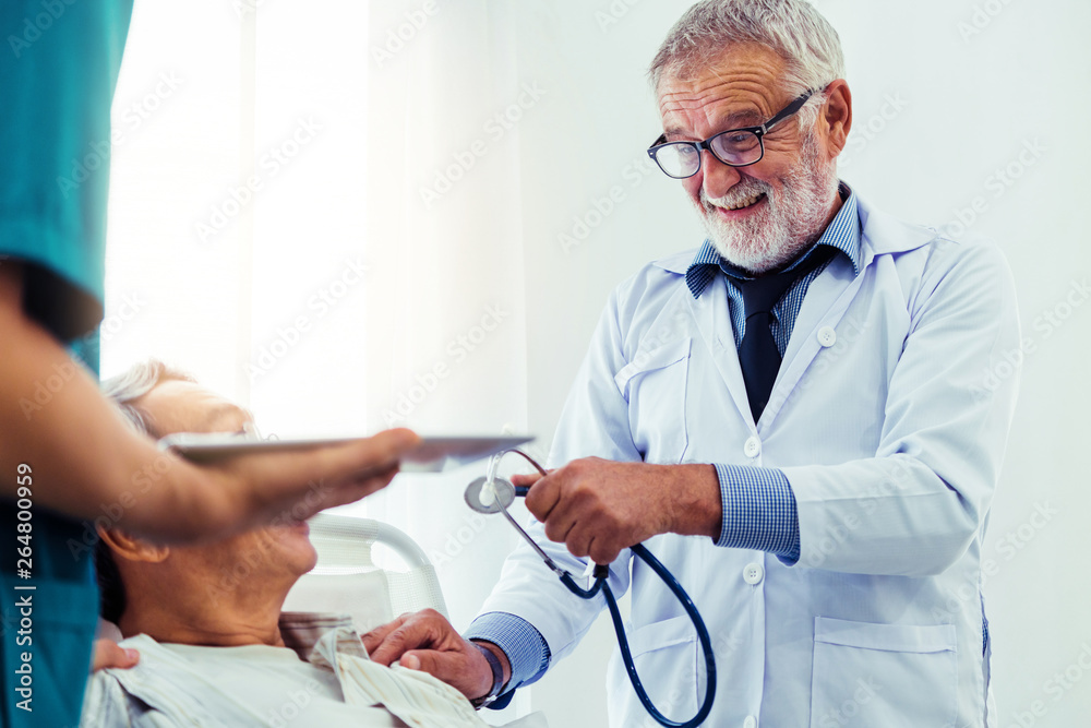 Mature doctor talking and examining health of senior patient in hospital ward. Medical healthcare an