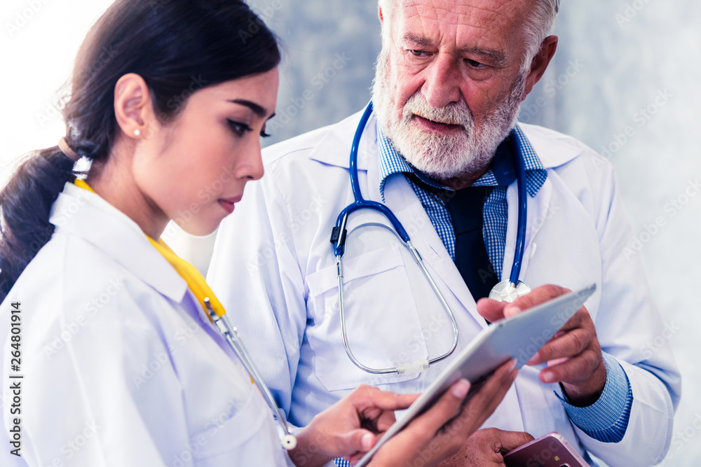 Senior male doctor using tablet computer while discussing with another doctor at the hospital. Medic