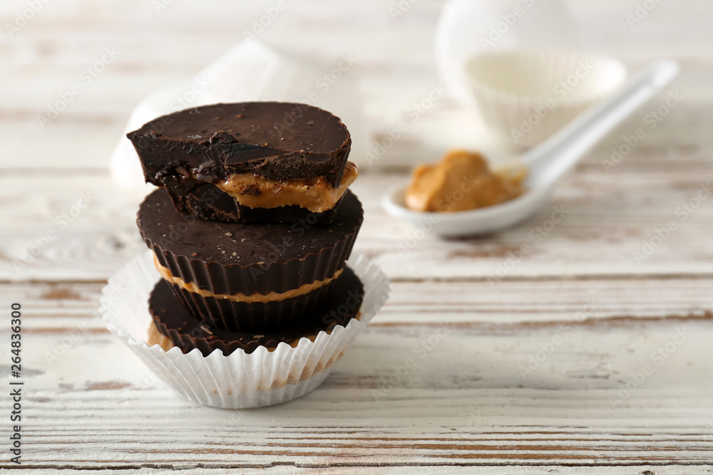 Tasty chocolate peanut butter cups on white wooden table