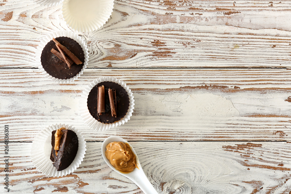 Tasty chocolate peanut butter cups on white wooden table