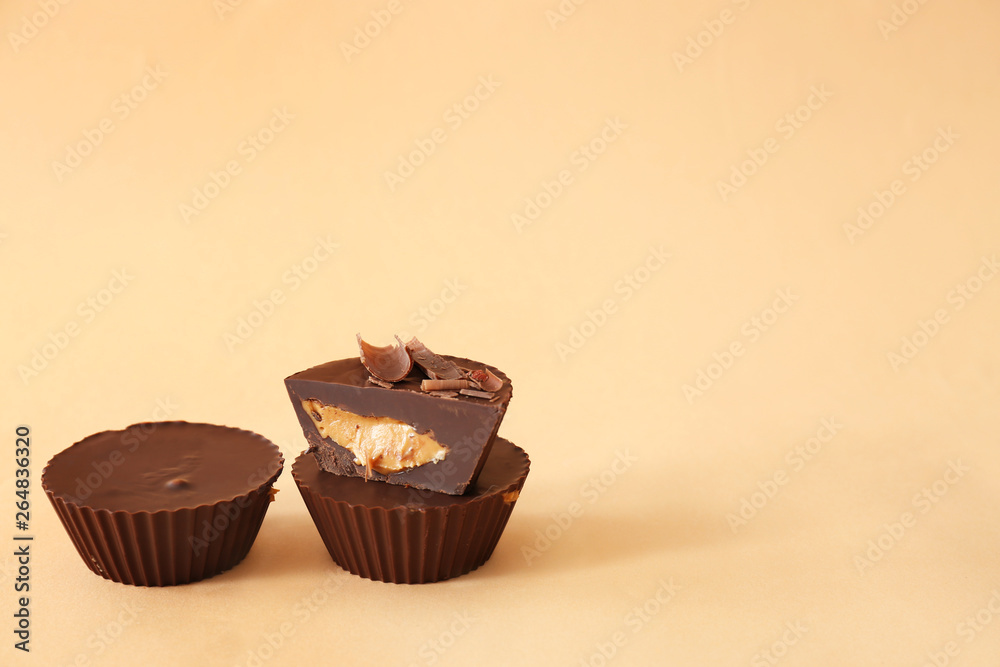 Tasty chocolate peanut butter cups on color background