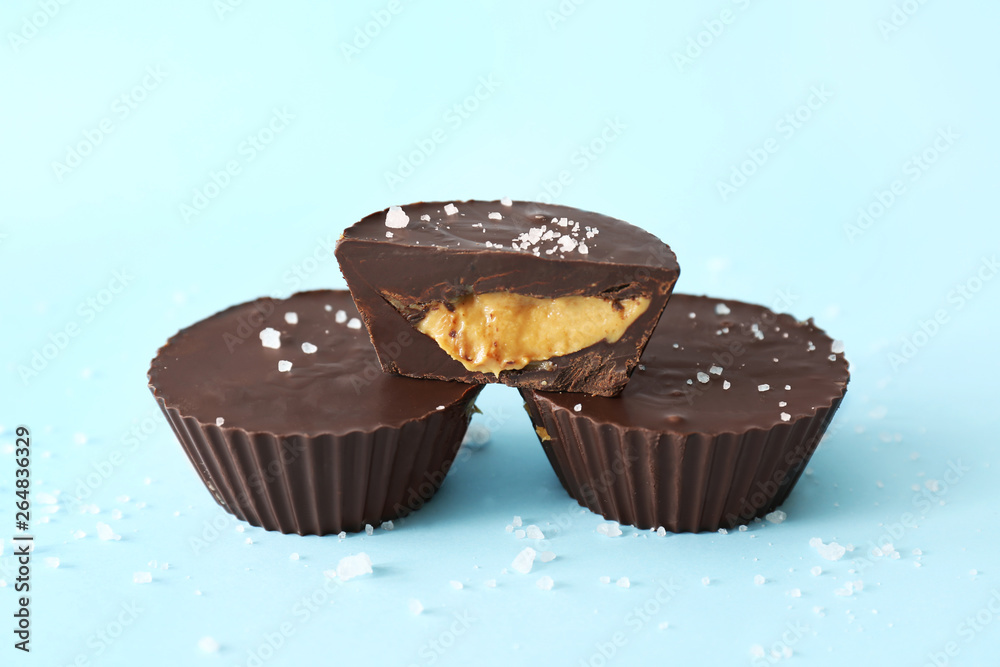 Tasty chocolate peanut butter cups on color background