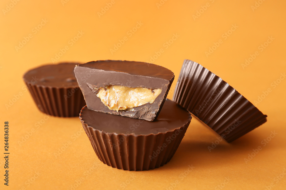 Tasty chocolate peanut butter cups on color background