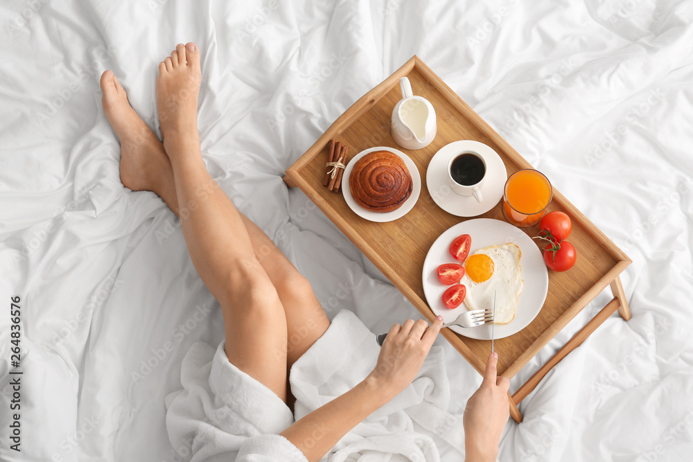 Woman having tasty breakfast in bed