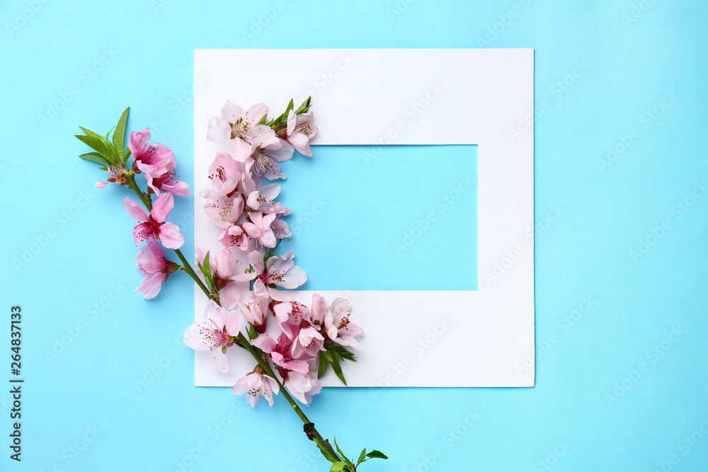 Beautiful blooming branch and paper frame on color background