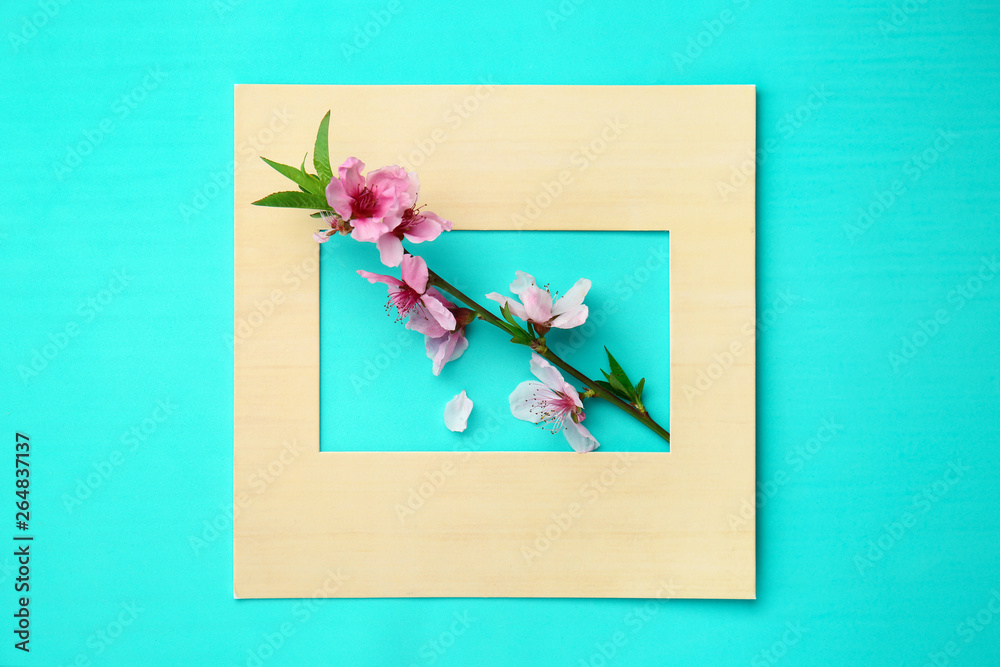 Beautiful blooming branch and paper frame on color background