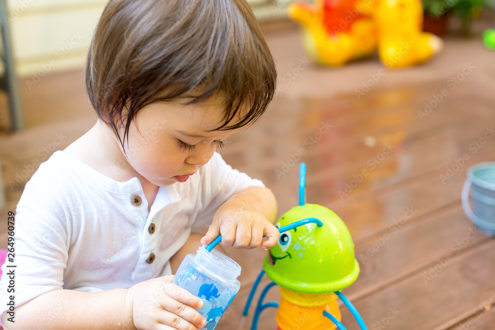 Toddler boy playing with a water sprinkler outside