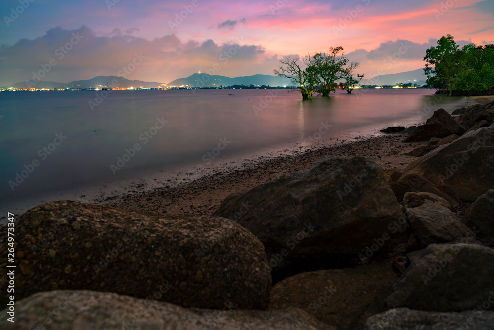 Long exposure image of Dramatic sky seascape with rock in sunset scenery background