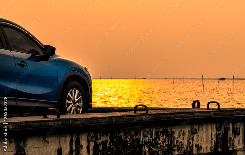 Blue compact SUV car with sport and modern design parked on concrete road by the sea at sunset. Envi