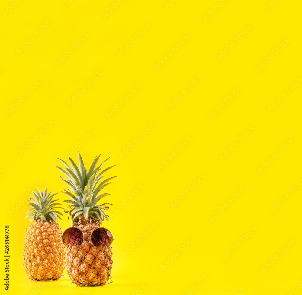 Creative pineapple looking up with sunglasses and shell isolated on yellow background, summer vacati