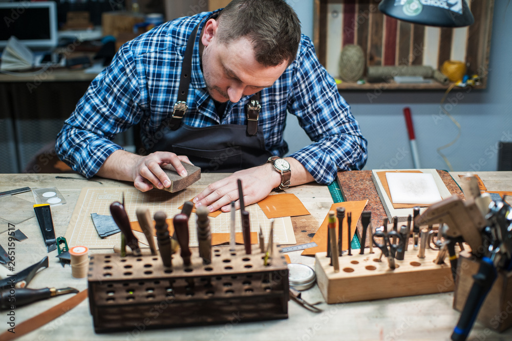 Man working with leather textile at a workshop.