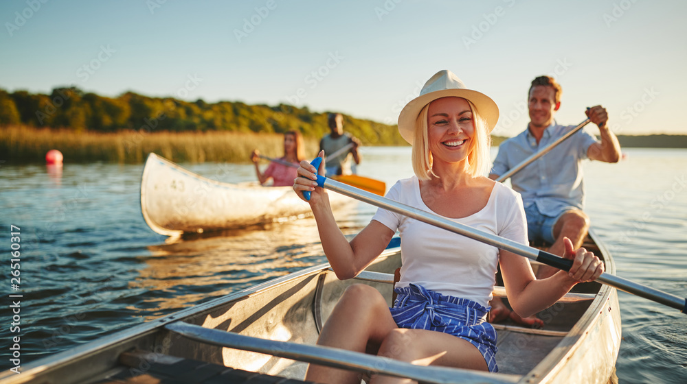 Laughing young woman canoeing with friends on a sunny afternoon