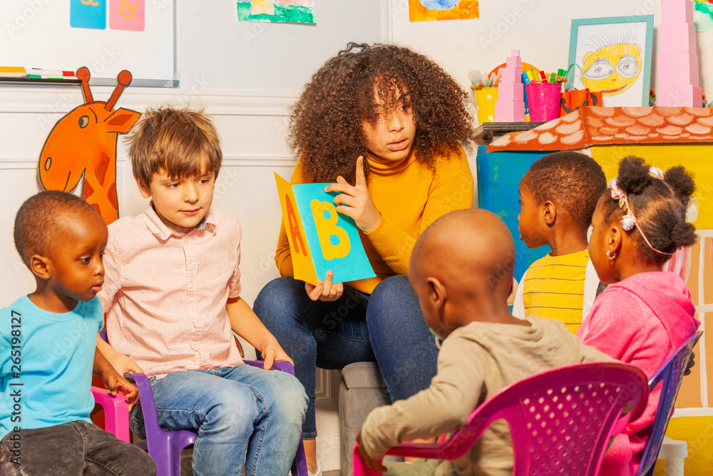 Little kids learn letters on alphabet in nursery