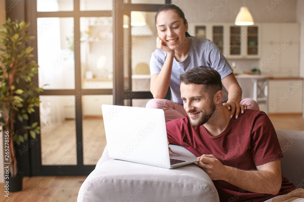 Happy young couple with laptop at home