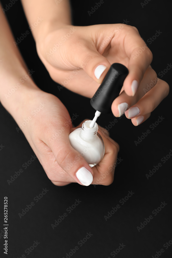 Woman doing manicure on dark background