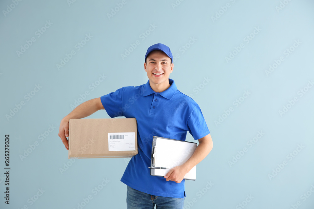 Delivery man with box and clipboard on color background