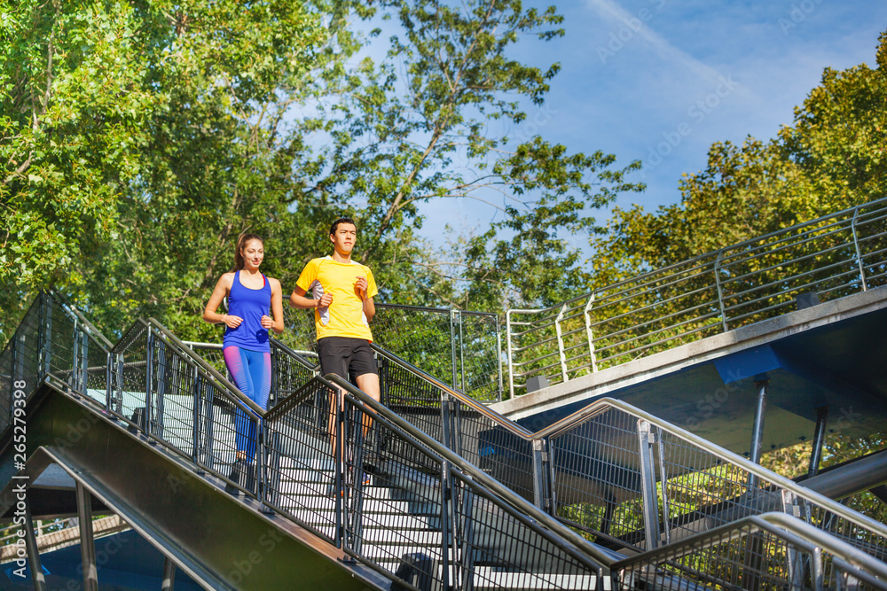 Sporty couple running downstairs at city park