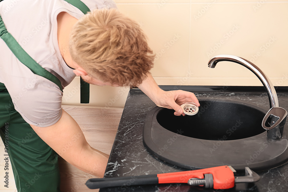 Plumber repairing sink in kitchen