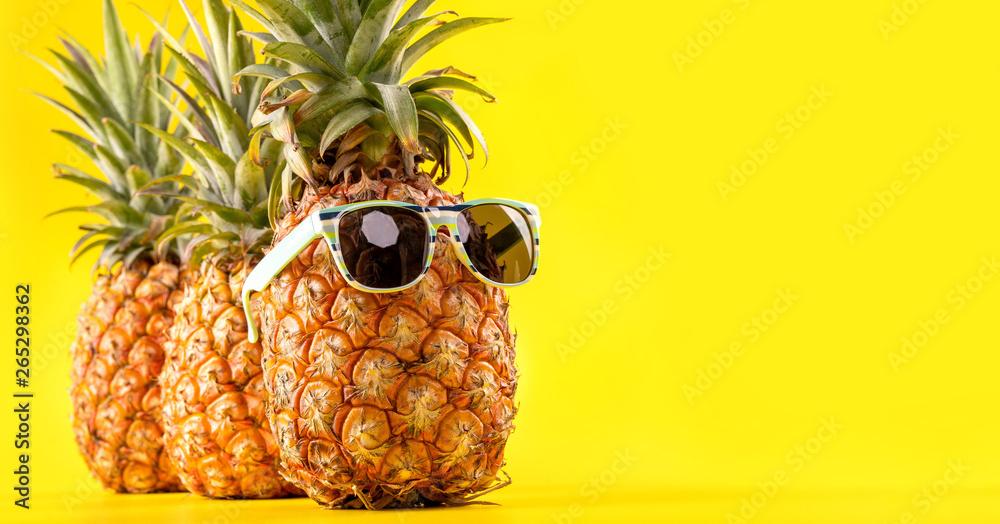 Creative pineapple looking up with sunglasses and shell isolated on yellow background, summer vacati