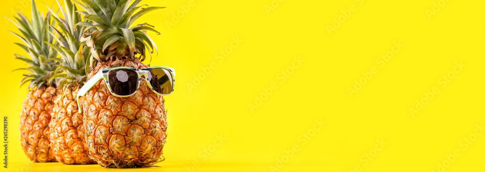 Creative pineapple looking up with sunglasses and shell isolated on yellow background, summer vacati