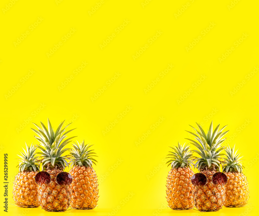 Creative pineapple looking up with sunglasses and shell isolated on yellow background, summer vacati