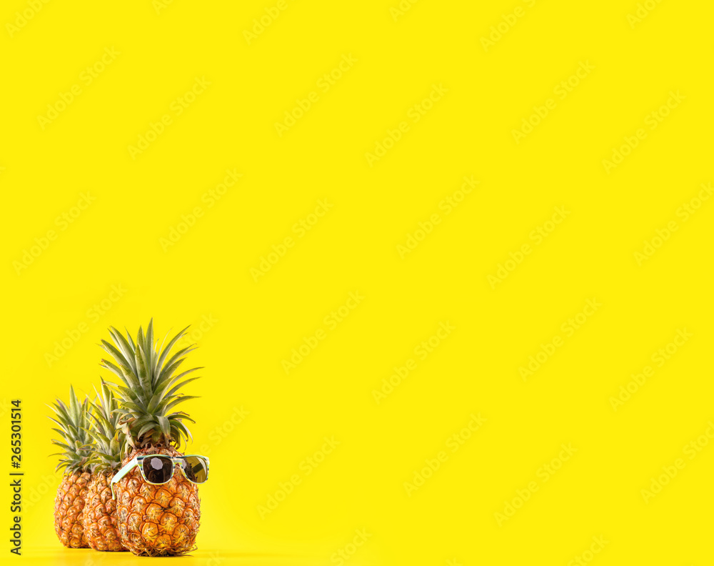 Creative pineapple looking up with sunglasses and shell isolated on yellow background, summer vacati