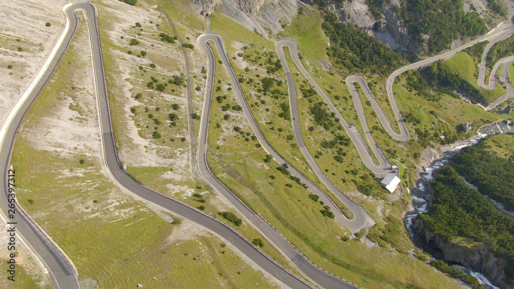 AERIAL: Flying above a scenic switchback road leading up to a mountain pass.