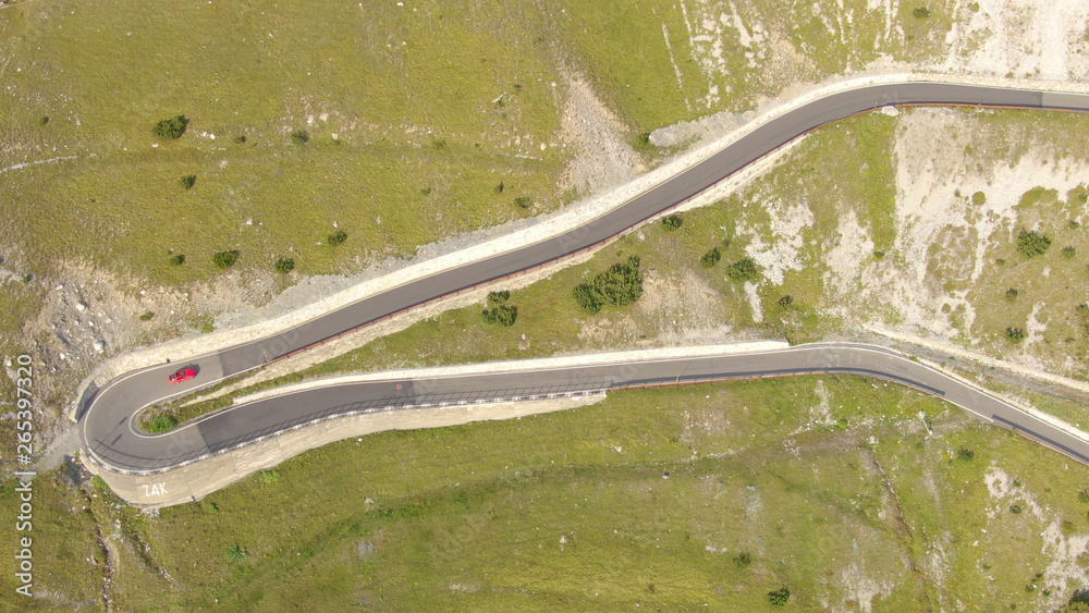 航空：红色跑车探索美丽的意大利阿尔卑斯山弯曲的道路。