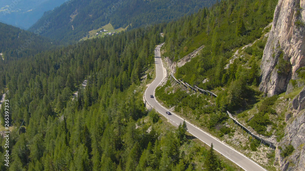 AERIAL: Two sports cars racing on a winding asphalt road in Dolomites Italy.