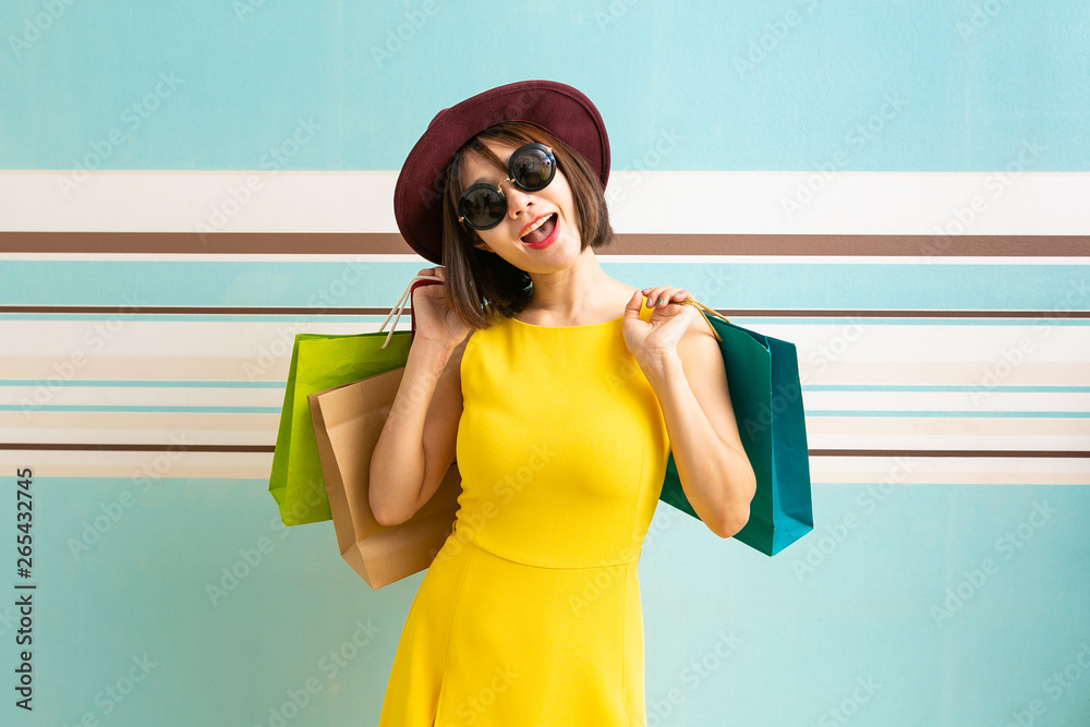 Portrait of beautiful girl wearing dress and sunglasses holding shopping bags.