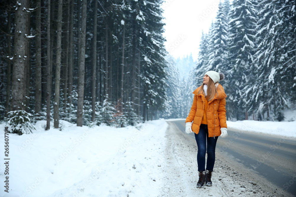 Beautiful young woman near road in winter forest