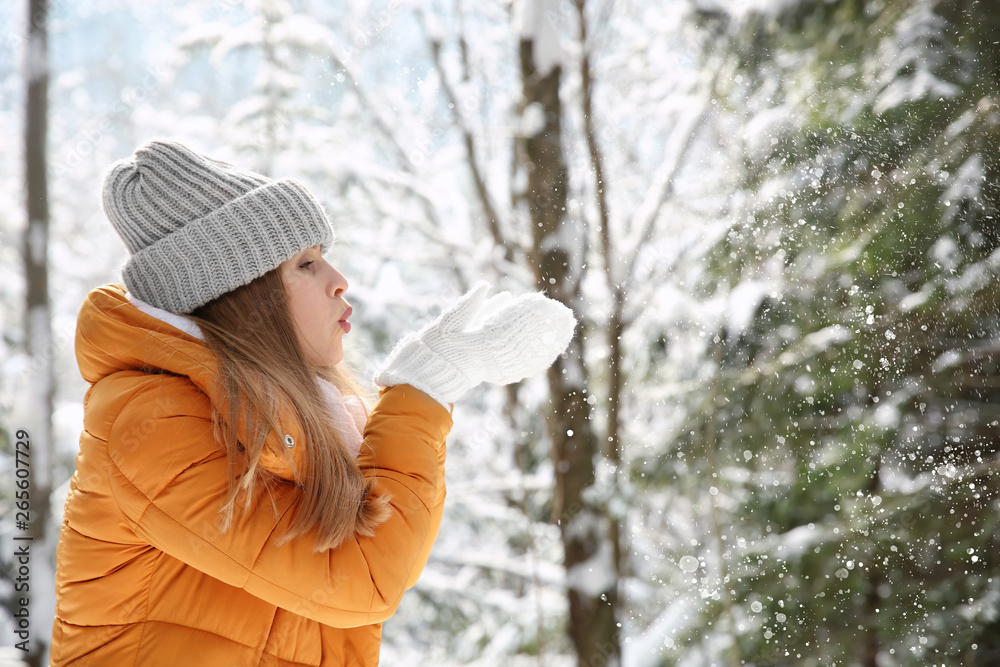 Beautiful woman playing with snow in winter forest