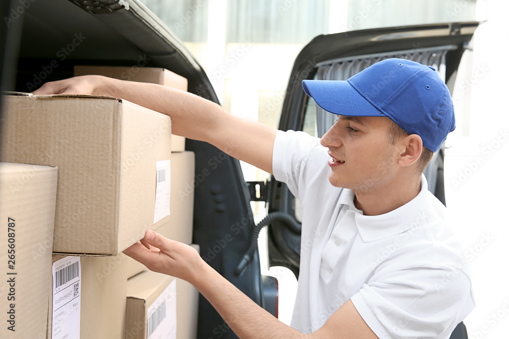 Delivery man taking parcel from car outdoors